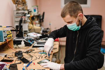 The technician repairing the smartphone motherboard in the lab. Concept of mobile phone,...