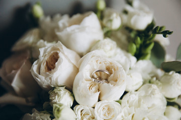 wedding ring lies on a bouquet of white flowers and greenery