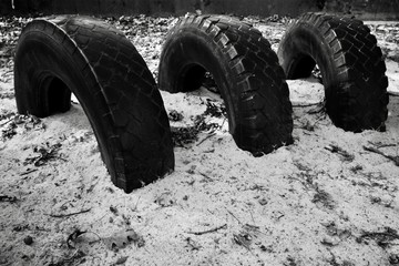 Fototapeta na wymiar car tyres background buried in sand black and white 