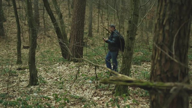 In the forest man uses smarphone walk smile feel happy technology park cellphone autumn traveller tree telephone mobile phone casual close up slow motion