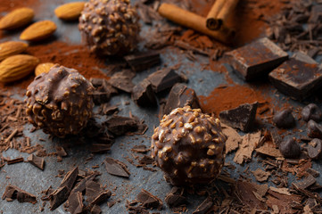 Homemade dark chocolate and almond nuts truffles surrounded by chocolate pieces and cocoa powder