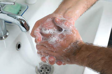 Fototapeta premium Man washing hands with soap and lathering suds. Protect against the coronavirus. Coronavirus pandemic protection by washing hands frequently. Hygiene to stop spreading coronavirus.
