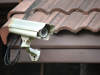 Old security camera or CCTV installed on the house roof. (security, safety, technology)