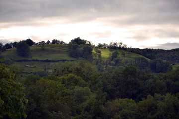 Beautiful green alpine hill, viewed from a garden. It is the evening, the sunset is beginning.