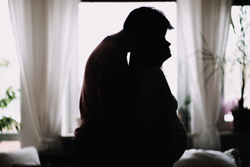 silhouette of future parents with belly of pregnant wife inside their home