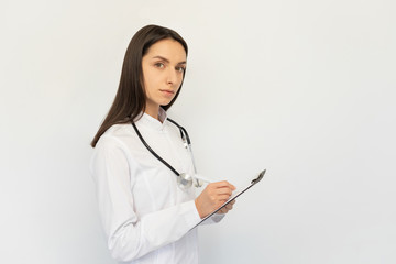 Friendly female doctor, writes the diagnosis to the clients card, a stethoscope on his neck