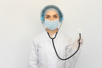 A doctor in a protective medical mask with a stethoscope in his hands