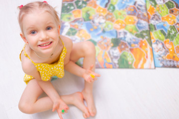 Board game concept. Little kid girl play in board game at home sitting on a wooden floor. Board game field, many figures.