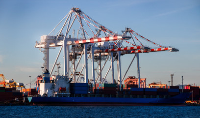 Fototapeta premium Logistics and container loading by large barges by sea in a harbor full of containers waiting to be transported