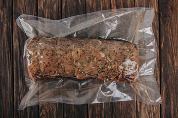 whole pork sausage in a vacuum pack on a wooden background. without label.