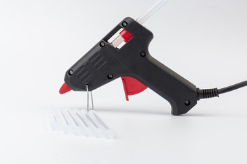 Electric hot glue gun on white background. Rods for glue gun