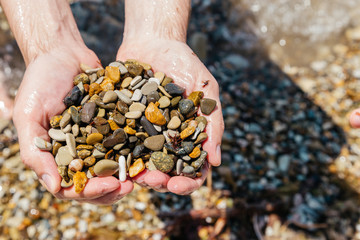 Man holds a sea pebble in his hands.