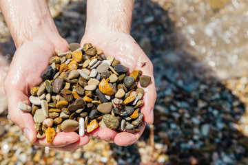 Man holds a sea pebble in his hands.