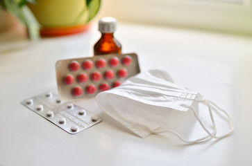  medical face mask and many different pills in blisters. Photo on a white background with bokeh.