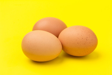 Brown eggs close up, isolated on yellow background. space for text