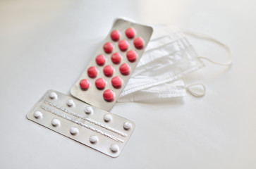  medical face mask and many different pills in blisters. Photo on a white background with bokeh.