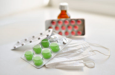  medical face mask and many different pills in blisters. Photo on a white background with bokeh.