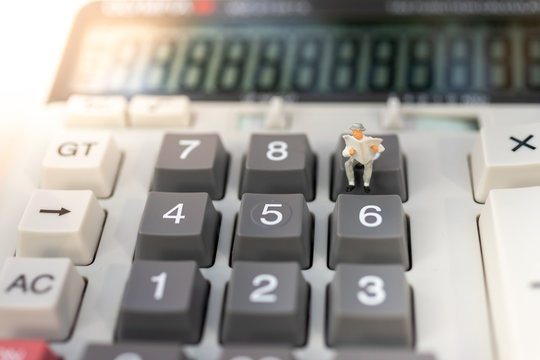 Miniature people: Businessman stand on calculator, tax, profit margins of  background. Image use for business concept.