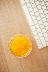 Orange juice and keyboard. Home office at quarantine. Top view. Focus on the glass