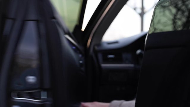 Closeup woman is opening black door and getting into car
