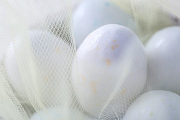 Easter sweet eggs or candies on a white transparent cloth. Decoration for the holiday. Shallow...
