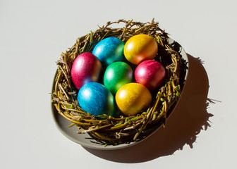 Colorful easter eggs in nest on white background with shadow.