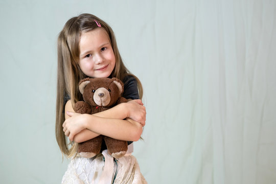 Pretty child girl playing with her teddy bear toy.