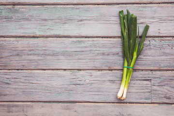 A bunch of fresh spring onions on a rustic wooden background