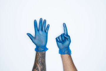 A man hand and gestures in Blue rubber glove shows six finger sign isolated on white background.