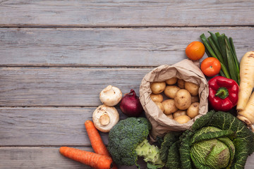 Layflat composition of fresh vegetables arranged on a wooden background