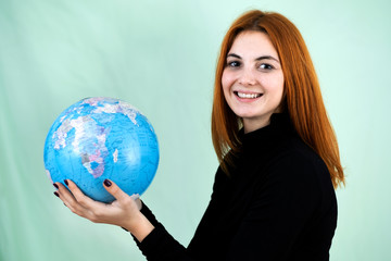 Portrait of a happy young woman holding geographic globe of the world in her hands. Travel destination and planet protection concept.