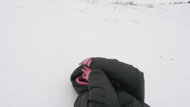 Woman lies on snowy ground. She protects her face with hands. Then man's hand grabs her.