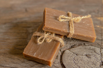 Two pieces of handmade soap tied with jute rope, vintage wooden background.
