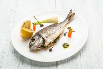 Grilled fish on platter isolated on white. Top view of whole roasted dorado