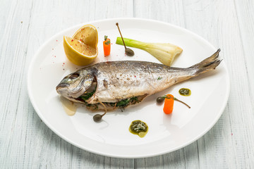 Grilled fish on platter isolated on white. Top view of whole roasted dorado