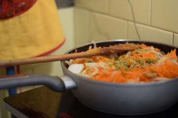 Frying pan with vegetables on the stove in the kitchen