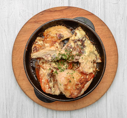 Baked spicy chicken legs in garlic sauce in a cast iron pan