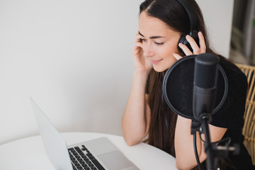 Woman blogger recording radio podcast in studio.