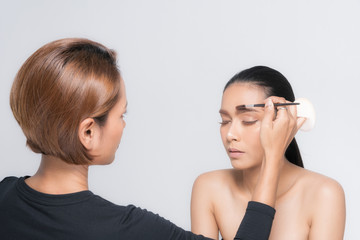 Woman applying makeup by makeup artist.