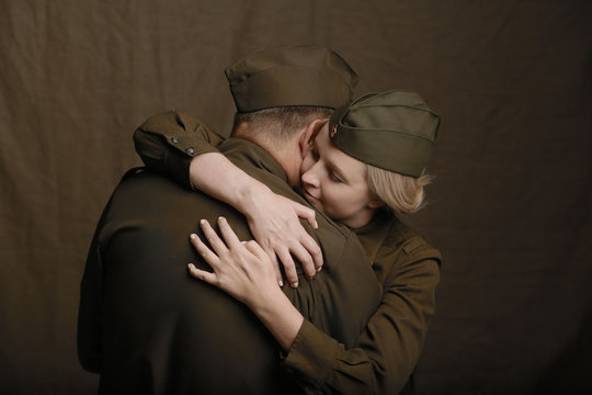 Young couple in love in world war Second military uniform hugs as if saying goodbye on brown background