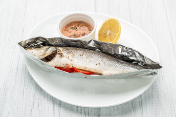 Baked sea bass with vegetables close up shoot on wooden background