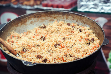 Tasty pilaf at street festival. Street market. Hot pilaf in large cauldron outdoors. Traditional oriental food.