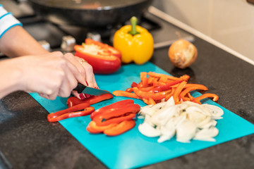 Woman slicing peppers in the kitchen preparing meal