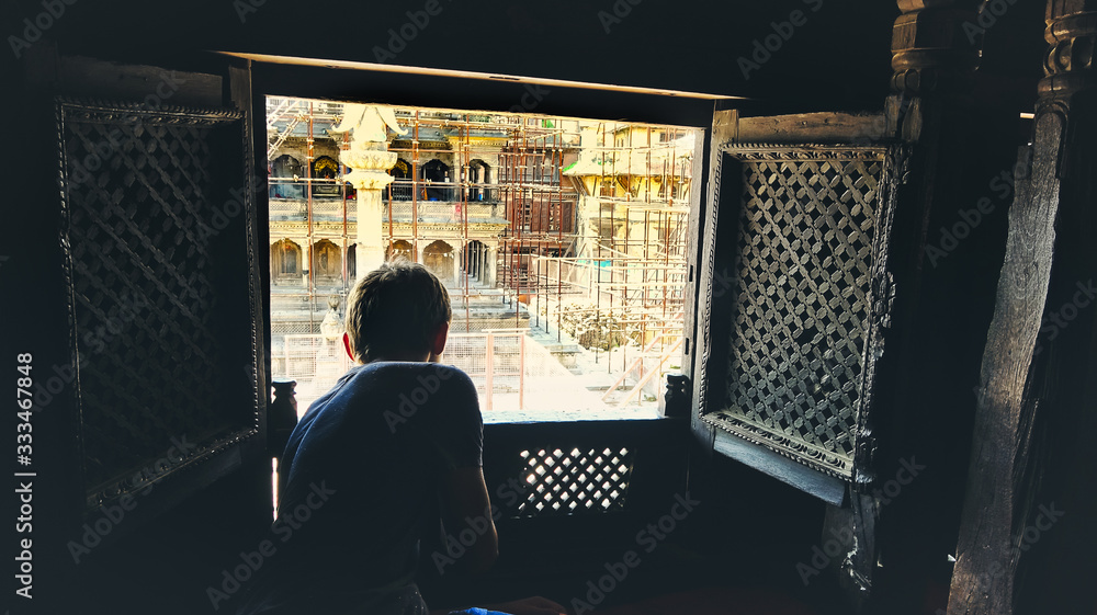 Wall mural boy looking out of nepalese window