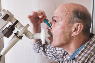 Senior hispanic man man testing breathing function by spirometry.