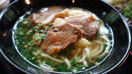 Asian style soup with udon noodles, pork, boiled eggs, mushrooms and green onions close-up in a bowl on the table. horizontal top view from above