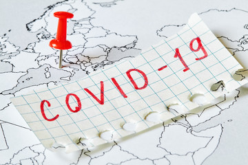 Map of Europe with red pushpin that marked Italy where is covid-19 epidemic and the inscription COVID-19 on a piece of paper. Concept of the spread of the virus.