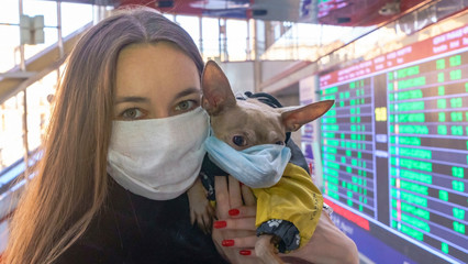 Woman in protective surgical mask holds dog pet in face mask. Chinese Coronavirus disease COVID-19 is dangerous. Protection coronavirus. Covid-19 concept.