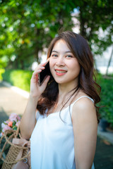 Beautiful women talking with smartphone in city park green tree background