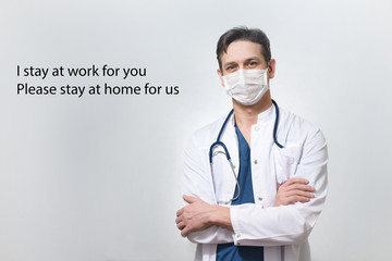 Fototapeta premium Stay at home caption on the photo of medical doctor in protection mask against Coronavirus or Covid-19 epidemic